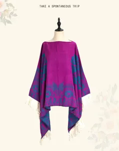 Detailansicht eines magenta-farbenen Ethno-Ponchos mit weißen Fransen auf einer Schaufensterpuppe.