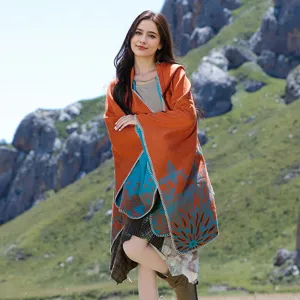 Detail shot of women's hooded knit poncho with orange and blue floral pattern.