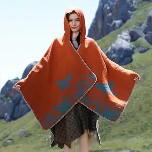 Detail view of women's orange hooded knitted poncho with blue butterfly patterns.