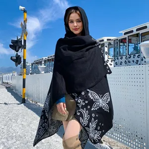 Detail of hooded black knitted shawl with white butterfly pattern on a model