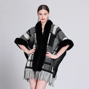Detailansicht eines modischen geometrischen Karo-Ponchos mit Pelzkragen und Fransen am Saum