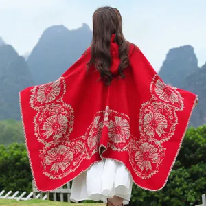 Rückansicht eines roten Strickponchos mit Kapuze und floralem Muster in der Natur
