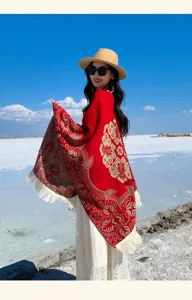 Detailansicht eines roten Ethno-Schals mit Quasten und Jacquard-Muster vor blauem Himmel