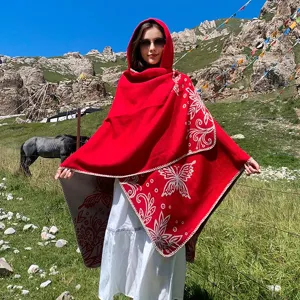 Outdoor lifestyle shot of a woman wearing a red hooded butterfly knit shawl poncho
