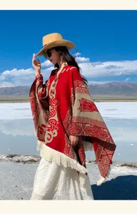 Model trägt einen Ethno-Jacquard-Poncho-Schal mit Quasten in einer schönen Außenlandschaft