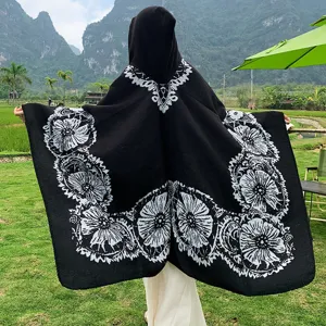 Detaillierte Rückansicht des schwarzen Kapuzen-Strickponchos mit weißem Blumenmuster