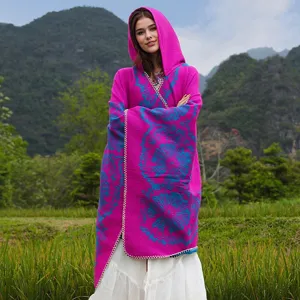 Lebhafter fuchsiafarbener Strickponcho mit blumenmuster und Kapuze in freier Natur