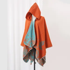 Close-up detail of an orange and teal hooded knit poncho with butterfly patterns