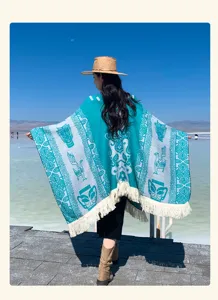 Türkisfarbener Ethno-Jacquard-Poncho-Schal mit Fransen in einer malerischen Außenanlage