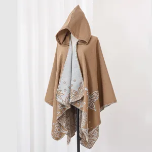 Detail of a brown knitted hooded poncho with grey butterfly floral jacquard pattern