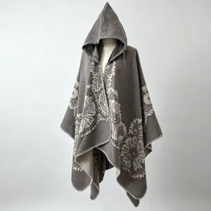 Detailansicht eines grauen gestrickten Ponchos mit Kapuze und elegantem Blumenmuster