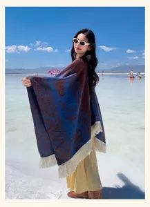 Detailaufnahme des Bohemian Jacquard Poncho Schals mit Quasten in malerischer Seekulisse