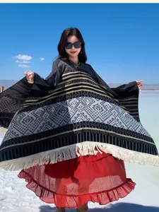 Detailansicht eines ethnischen Quasten-Ponchos in einer sonnigen Außenlandschaft getragen.