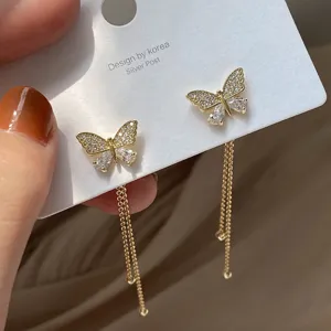Close-up of butterfly stud earrings with rhinestones and long gold tassels on a card