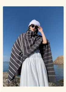 Detailed outdoor view of a bohemian striped knit shawl with fringe on a model by water