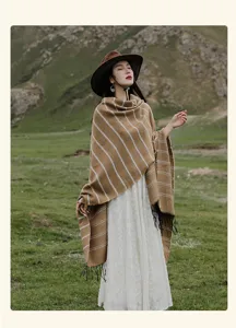 Model wearing ethnic style striped knit shawl with tassels in a mountainous landscape