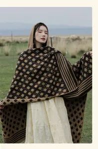 Detail view of ethnic style hooded knitted shawl with geometric pattern on a model.