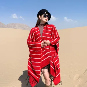 Red and white striped ethnic style knitted poncho with black tassels in desert setting
