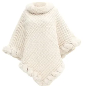 Close-up of oversized cream knit poncho featuring a soft faux rabbit fur collar
