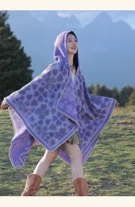Modell trägt ein lilafarbenes, ethnisches Strickponcho mit Herzmustern im Freien