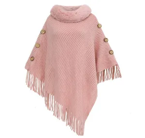 Detail view of pink knitted poncho featuring faux fur collar and tassels.