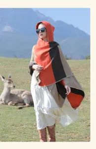 Woman wearing a hooded striped ethnic style shawl in an outdoor scenic mountain landscape.
