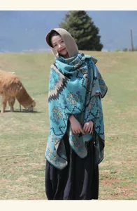 Châle ethnique à capuche avec motifs géométriques turquoise sur un champ de herbe vert