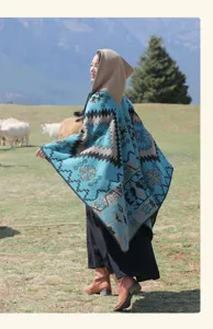 Châle poncho à capuche ethnique avec motifs géométriques en décor de montagne.