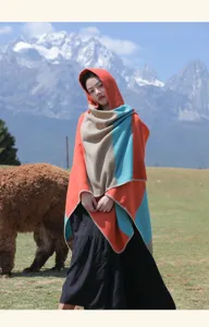 Asian model wearing an ethnic striped hooded poncho against a mountain backdrop