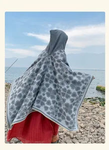Rückansicht eines Boho-Kapuzenstrickschals mit grauem Kleemuster am Seeufer.