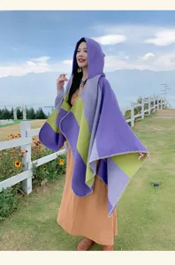 Model wearing ethnic style hooded striped shawl in a scenic mountain outdoor setting