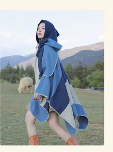 Detailed view of women's hooded striped knit poncho in an outdoor travel setting.