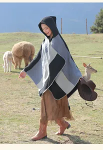 Full view of women's striped hooded poncho shawl in a scenic travel lifestyle setting