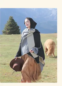 Model wearing a hooded striped ethnic shawl in outdoor grassland with an alpaca.
