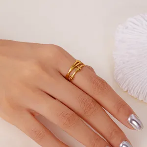 Nahaufnahme eines vergoldeten Edelstahlrings mit mehrschichtigem Design an einer Hand.