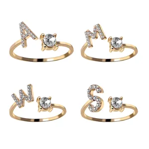 Detail of four crystal-encrusted initial rings in gold finish with large solitaire gems
