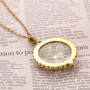 Close-up detail of a vintage gold hollow magnifying glass pendant on newspaper background