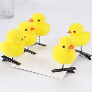 Detailansicht von fünf flauschigen gelben Enten-Haarklammern mit Feder und Clip.