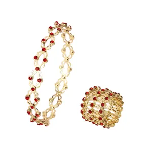 Dettaglio di anello e bracciale trasformabili in rame placcato oro con cristalli rossi.