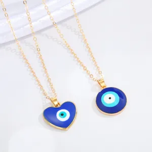 Close-up of heart and round Evil Eye necklaces with blue enamel and gold chains.