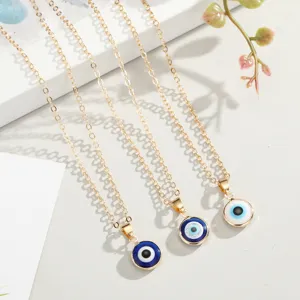 Close-up detail of three gold-plated Turkish evil eye pendant necklaces in various blue shades