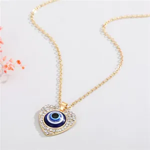 Macro view of a gold heart-shaped evil eye necklace pendant with crystal border