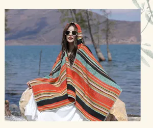 Ethnic style hooded poncho with colorful stripes worn by a model in a scenic setting