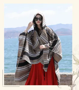 Bohemian style hooded poncho with ethnic stripes worn by a model in a scenic lakeside setting