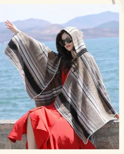 Outdoor shot of a woman wearing a bohemian striped hooded knit shawl by the lake