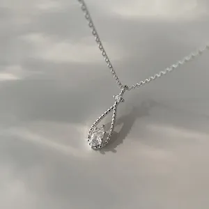 Detalle de un colgante de gota de agua plateado con una piedra preciosa brillante.