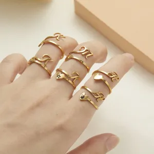 Close-up detail of adjustable gold stainless steel rings with initials and heart designs