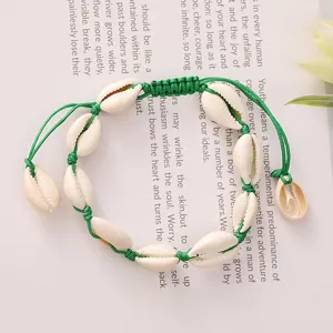 Close-up detail of a beach style shell bracelet with green woven adjustable cord