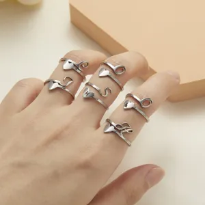 Close-up of heart-shaped stainless steel initial rings worn on female hand