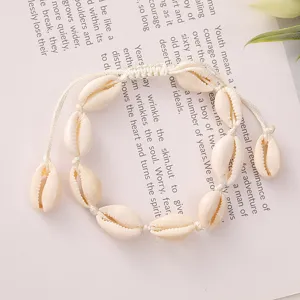 Detail shot of a handmade woven bracelet with natural cowrie shells on a soft background.